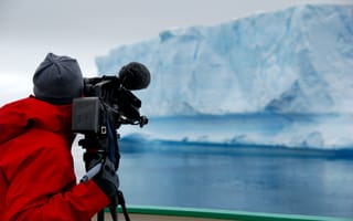 mera operator in a bright red coat filming an iceberg in Antarctica