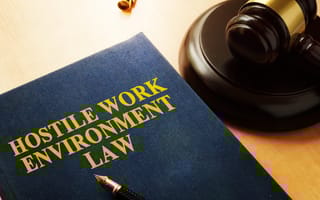 A textbook titled "Hostile Work Environment Law" is pictured on a desk next to a judge's gavel.