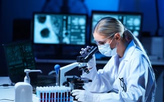 A scientist looks through a microscope.
