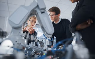 Two people work on a robotic system.