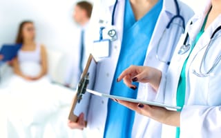 Two doctors interact with a tablet.