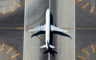 An aerial view of a passenger airplane sitting on an airport runway.