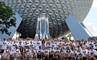Large group photo of Kustomer team members wearing matching Mickey Mouse-themed t-shirts in front of the Epcot Center’s Spaceship Earth.