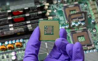 A gloved hand holds a semiconductor chip.