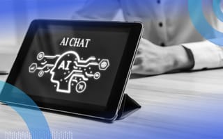 A close-up of a propped-up iPad with “AI CHAT” on the screen and a business person sitting across from it.