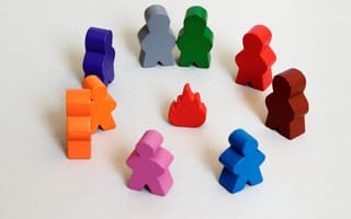 Colorful wooden figurines stand in a circle around a fake fire.