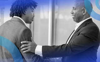 An older businessman reassuringly touching the arm of a younger businessman.