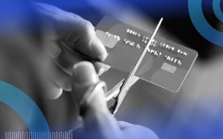 A close-up of someone cutting their credit card in half with scissors.