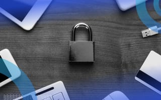 A locked padlock on a table surrounded by a smartphone, credit card, iPad, computer keyboard, computer mouse and USB.