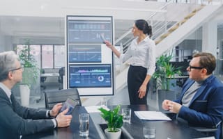 Finance executives analyze metrics on a screen.