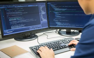 A software developer writes on code.