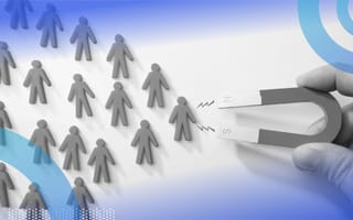 A close-up of someone holding a magnet that’s attracting tiny people-shaped objects.