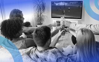A group of people watching TV and holding up glasses of non alcoholic beverages.