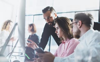 Team members in office looking at data on computer monitor