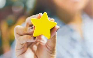 A hand holds up a gold star.