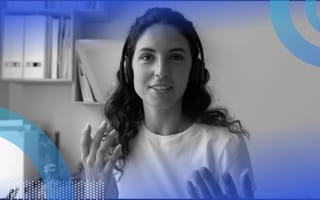 A young woman wearing headphones is watching a computer screen and making hand gestures.