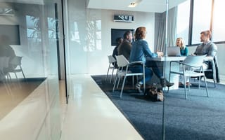A group of five business professionals sit around a conference table.