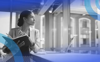 A CEO sitting at a table and looking out a window in a contemplative way.