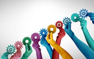 Hands of different vibrant hues hold interconnected gears.