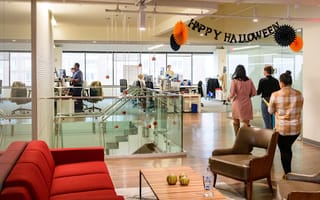 CarGurus office interior with employees milling about and a “Happy Halloween” banner hanging from the ceiling.