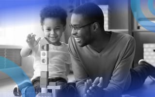 A smiling father and toddler playing with blocks.