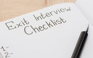 A pen lies on an empty notebook page titled "exit interview checklist."