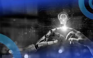 A robot hand and human hand touching index fingers with a lightbulb over them.