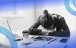 A woman is slumped over a desk in a despondent fashion.