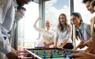 Employees playing a game of table soccer in company office