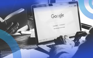 A computer has the Google home screen displayed. A person is typing on the keyboard.