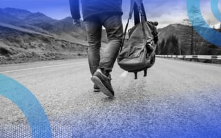 A person holding a knapsack is walking down a road.