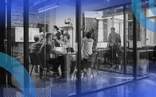 A group of tech employees celebrate in a glass conference room