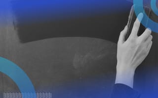 A close-up of someone’s hand wiping a chalkboard clean with an eraser.