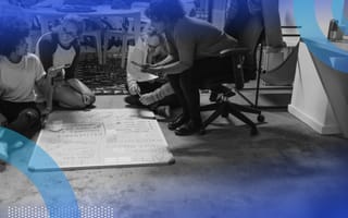 Four young people sitting and crouching on the ground over a project.