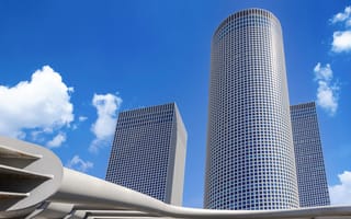 A photo of the Azrieli Center in Israel as seen from below with a clear blue sky.