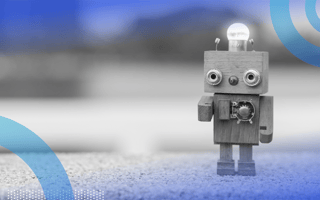 A tiny, retro wooden robot with a lightbulb on its square head.
