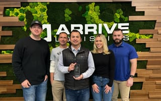 Five Arrive employees stand with an award in front of the company logo in its offices.