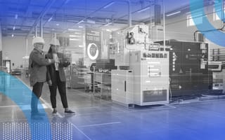 A man and woman in hard hats look at a tablet computer in a smart factory