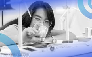 A woman with glasses is holding a light bulb and smiling.