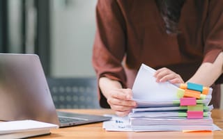 A HR professional sorts through a stack of papers containing HR metrics.