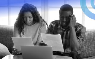 A Black couple looks frustrated as they review financial papers.