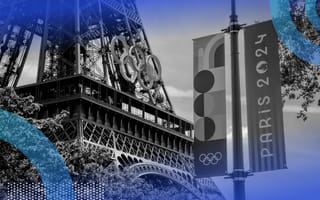 The base of the Eiffel Tower decorated with the Olympic rings and a sign announcing the Paris Olympics