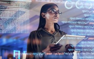 A woman with dark hair and brown skin and wearing glasses stands with a tablet. A transparent display of code overlays the image.