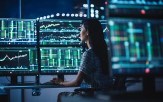 Financial analyst trades assets in multiple monitors.