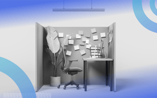 A side view of a cubicle with a large potted plant in the corner, rolling chair, desk, computer and sticky notes on the walls.