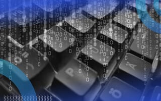 Binary, vertical code overlaying a close-up of a computer keyboard.