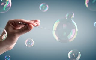 A photograph of bubbles floating in the air, and a hand holding a needle.