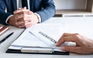 An employee places a resignation letter on their boss' desk.
