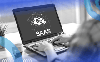 A computer screen reads SaaS and two hands are on the computer keyboard.