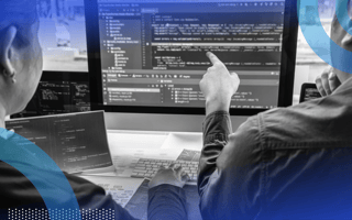 Two developers reviewing code on a terminal